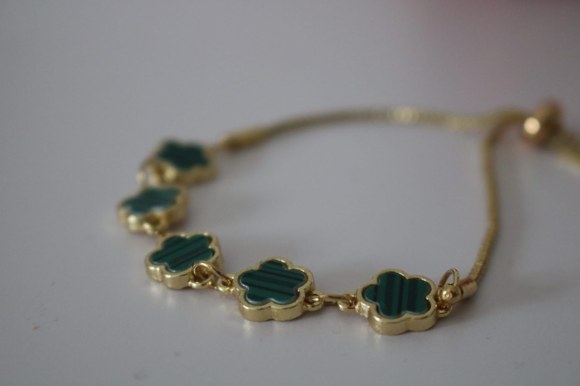 Gouden armband met groene bloemvormige schakels.